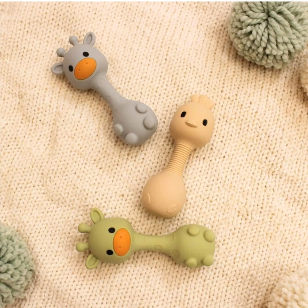 Animal Teething Rattles in giraffe and bird designs lying on a knitted blanket